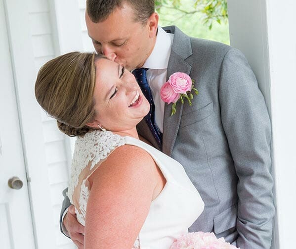 A bride and groom hugging in front of the door on a venue's porch