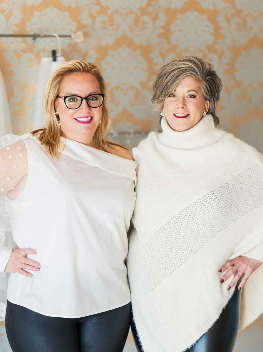 Two women standing next to each other in a bridal salon.