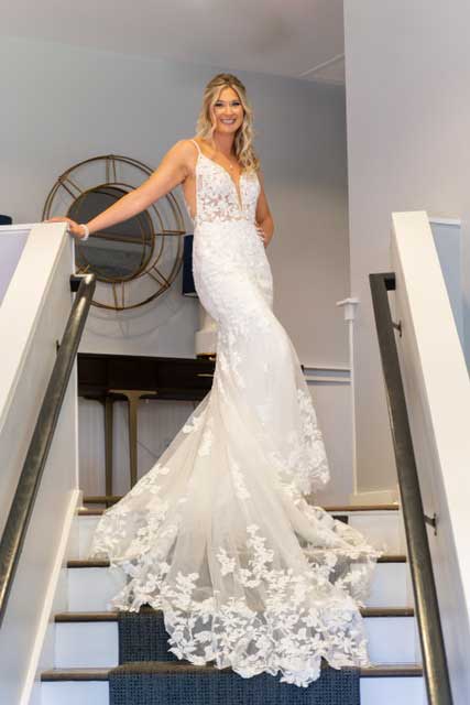 A bride standing on the stairs in a bridal salon wearing a wedding dress.