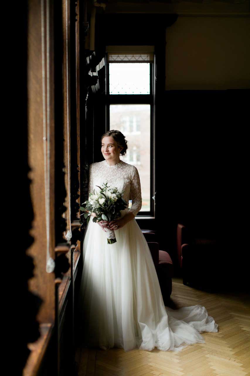A bride in a wedding dress standing in front of a window at a bridal salon.