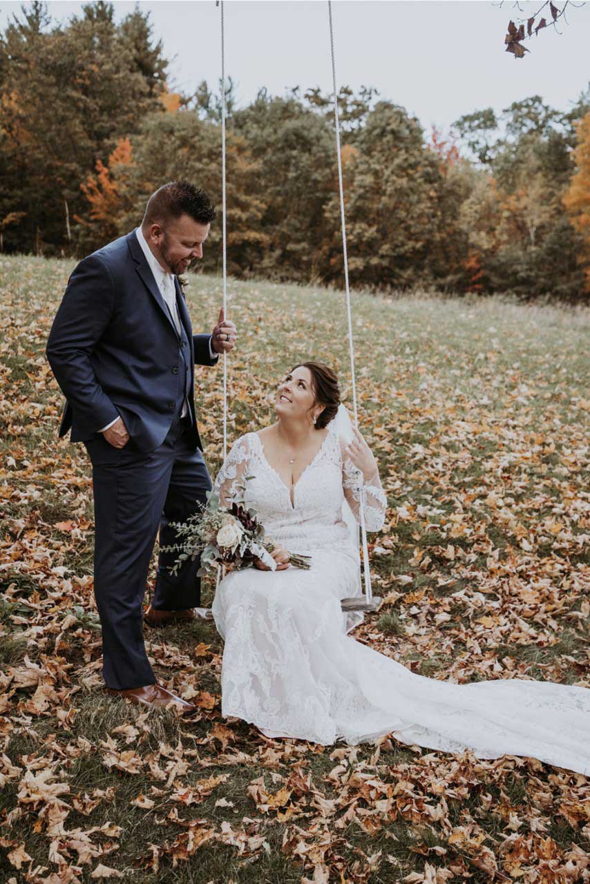 A bride and groom enjoying the autumn scenery while sitting on a swing in a bridal shop.