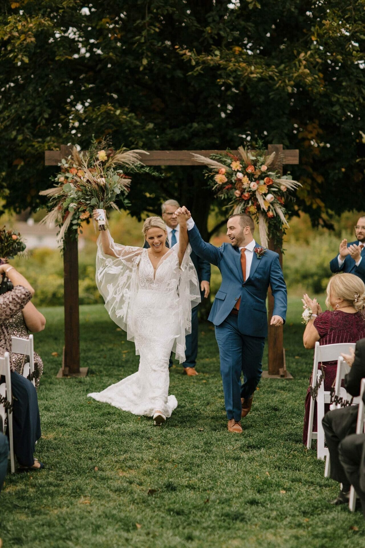 A bride and groom walking down the aisle at a fall wedding, beautifully attired in their exquisite wedding dresses from a renowned bridal salon.