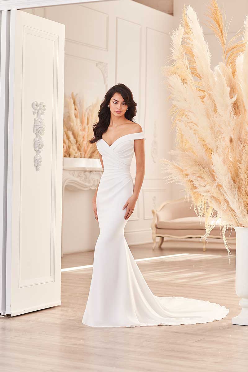 A woman in a white wedding dress is posing in a bridal salon.