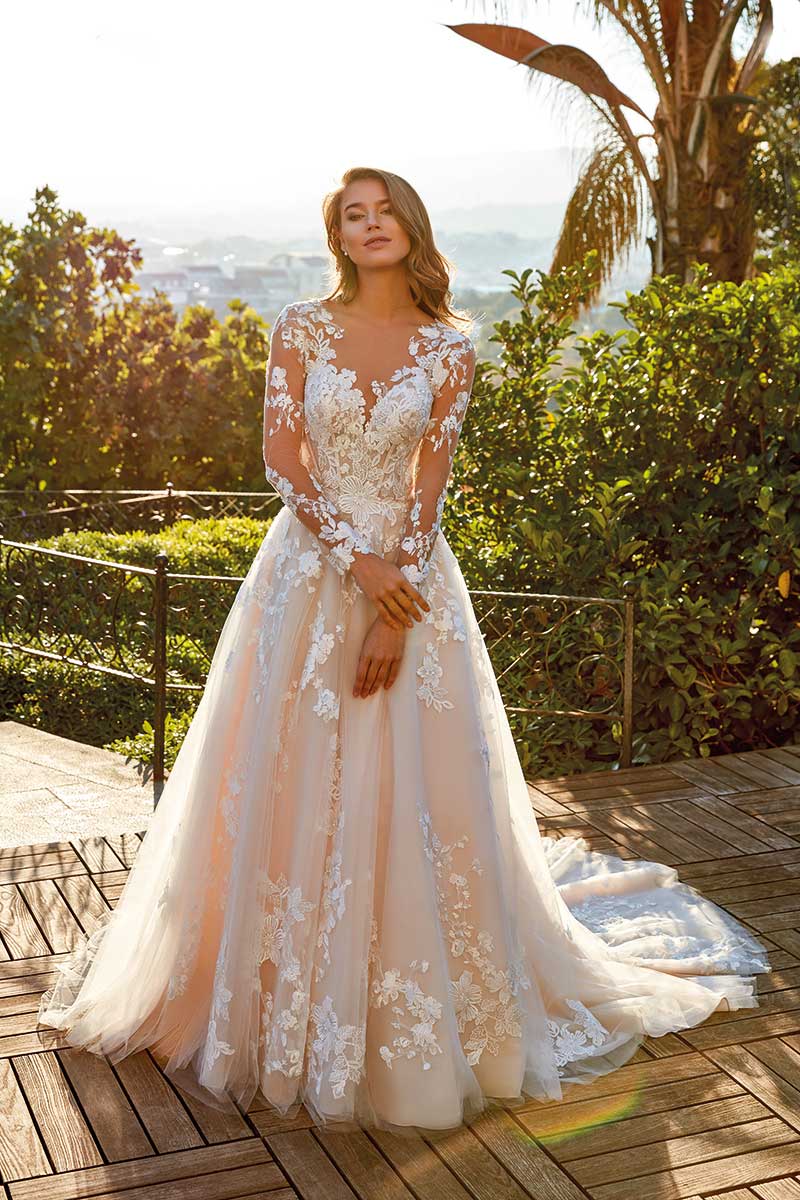 A beautiful bride in a long-sleeved wedding dress found at a bridal salon.