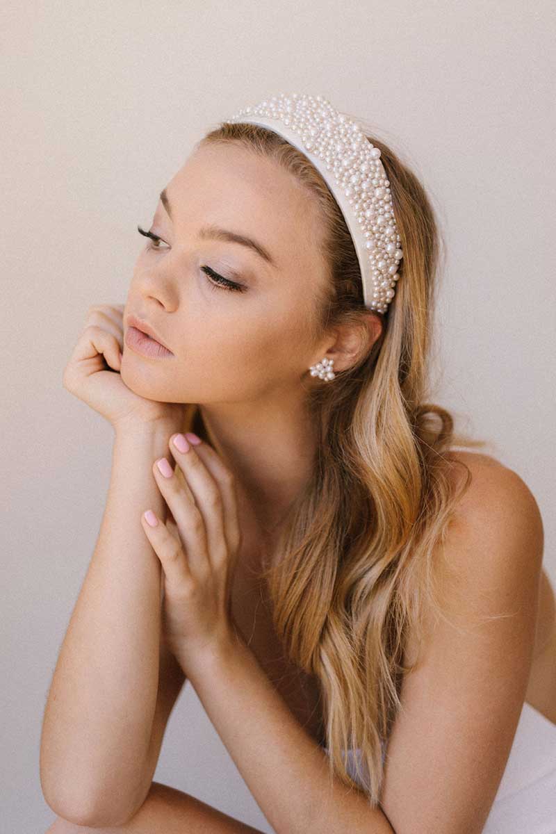 A stunning woman adorned with a pearl tiara browsing through wedding dresses at a bridal salon.