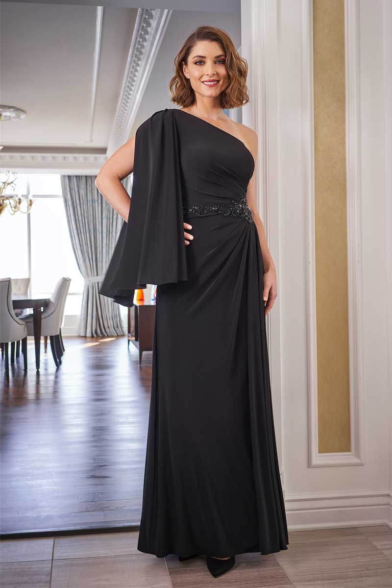 A woman is posing in a black evening gown at a bridal shop.