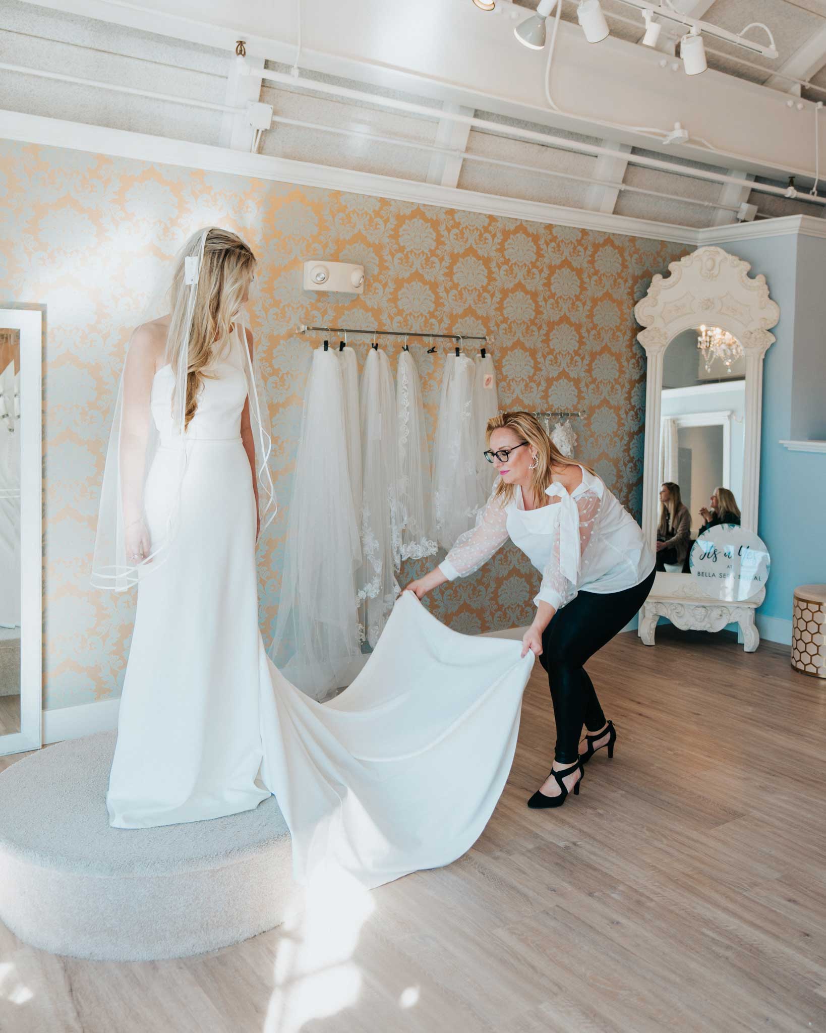 A woman is trying on wedding dresses in a bridal salon.