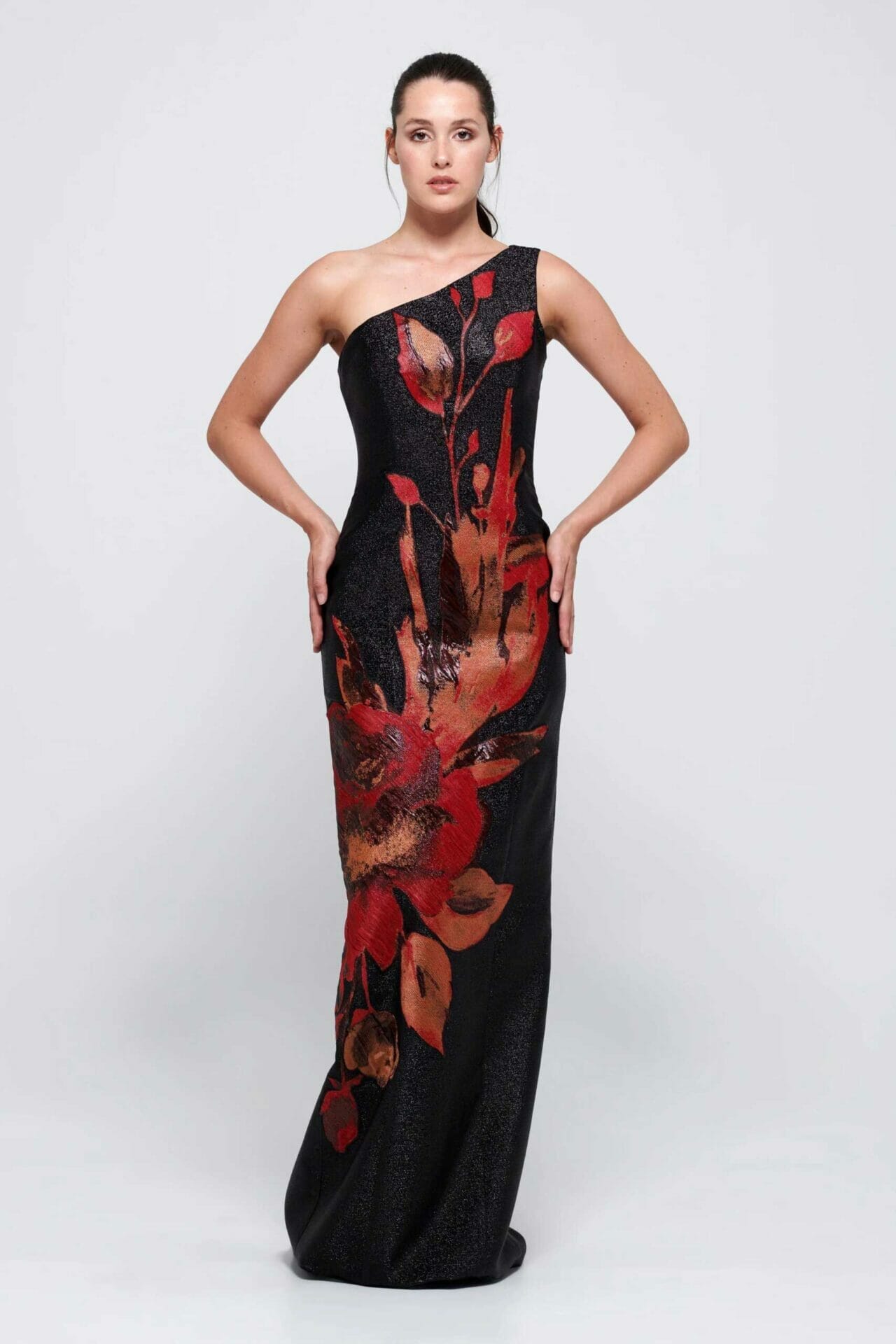 The model is wearing a black gown with red and black floral print
